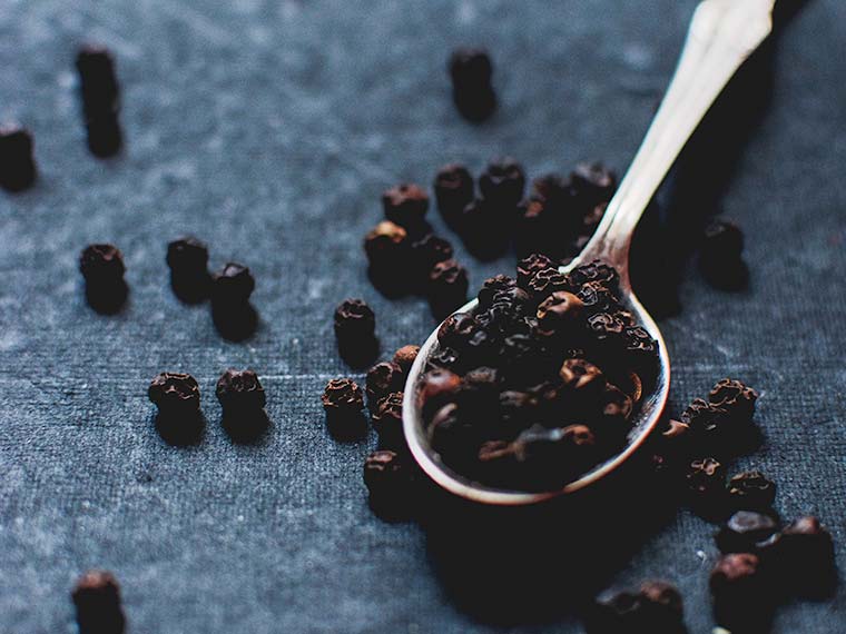 a spoon with black pepper