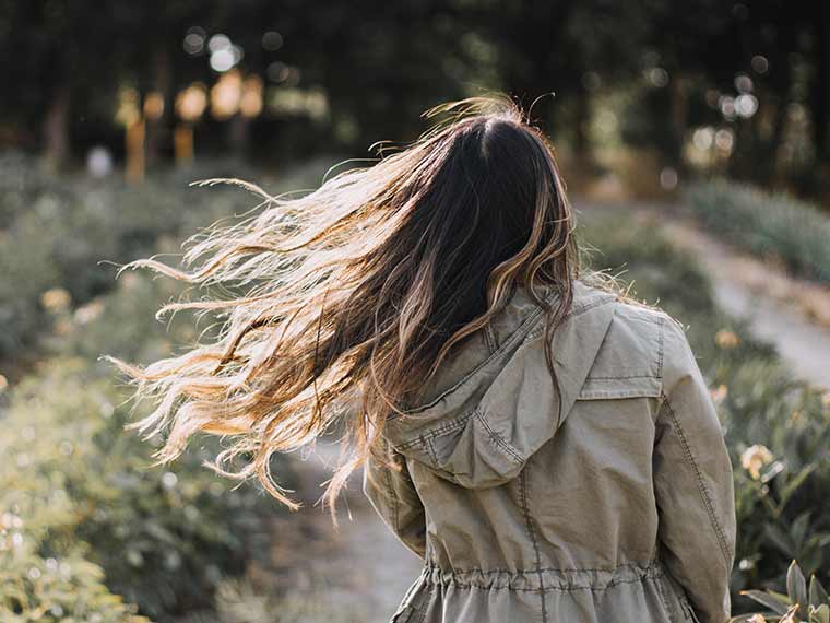 a woman walking through a row of flowers